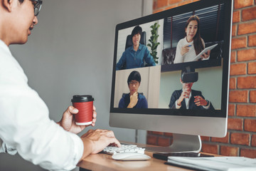 Asian man working from home use Smart working and video conference online meeting with Asian team using laptop and tablet online in video call for new projects