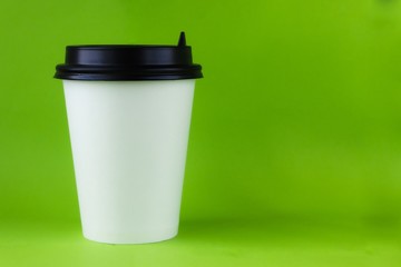 white paper cup for hot and cold drinks with a lid on a green background. ecology clean nature concept