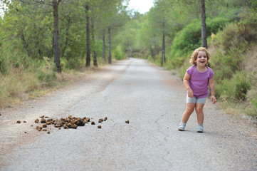 funny little child on the way surprised and laughing at horse droppings