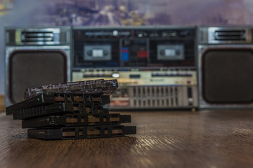 old vintage tape audio cassettes lying on wood surface with retro tape recorder on background. retro 90's music concept