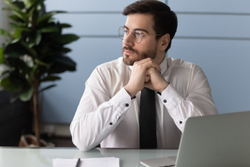 Thoughtful businessman using laptop, pondering online project or strategy, business vision, employee working on finance report, sitting at office desk, manager solving business problem.