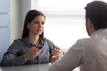 Happy smiling female applicant talking with hr manager employer at job interview. Woman candidate with businessman at meeting dedicated to employment and hiring decision.