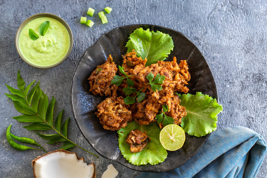 Indian cuisine. pakora traditional Indian deep-fried snack. pakoras on black plate with coconut chutney sauce. national appetiser authentic vegetarian food. Asian travel food. top view. copy space.