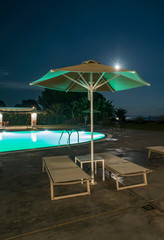 Pool, sunbeds and umbrellas at night