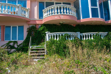 Abandoned hotel on the beach, covered in green grass and climbing ivy plant, nature take over concept, building facade