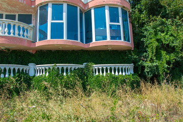 Abandoned hotel on the beach, covered in green grass and climbing ivy plant, nature take over concept, building facade