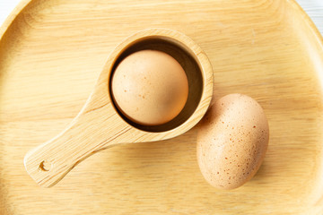 Raw fresh chicken eggs or boiled eggs in wooden spoon and plate