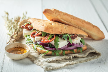 Sandwich with arugula, dried tomatoes, red onion and cheese
