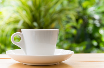 White coffee mug on wooden space background,  Back is a tree with a refreshing morning light.