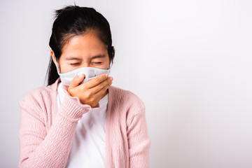 Asian woman wearing surgical protection cloth face mask hygiene against coronavirus and her sneeze hand close mouth, studio shot isolated on white background with copy space, COVID-19 concept