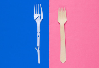 Minimalistic ecologically clean still life. Pop Art. Broken plastic fork and wooden fork on blue pink background. Cutlery made from natural materials, Top view