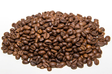 a pile of freshly roasted coffee beans isolated on a white background.