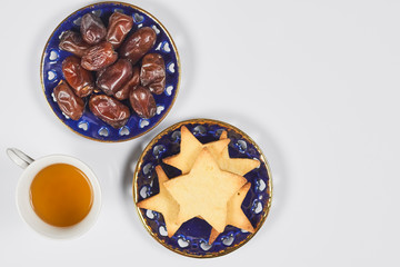 Iftar foods on white table. Traditional middle-eastern lunch with cookies and dry date fruits