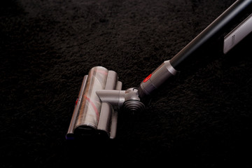 aspirateur sans fil sur un tapis noir © Guiolo