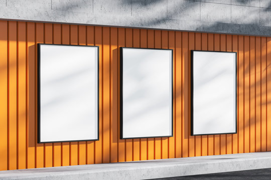 Three blank billboards on orange building wall