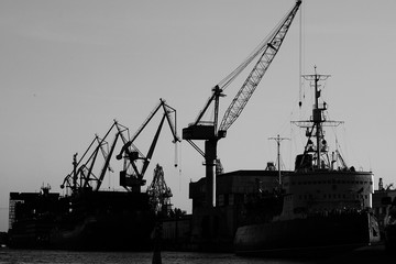 unloading a ship in port, ships standing near the shore, black and white photography