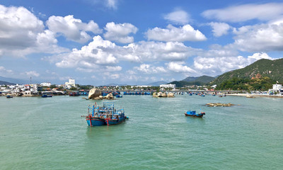 Bright fishing boats in the bay, Vietnam. blue boats with red details. Traditional Vietnamese buildings in the background