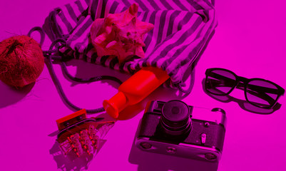 Creative vacation on sea Still life. Beach accessories in pink neon light with shadows