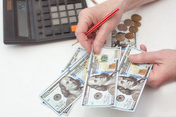 Close-up of hands counting money American dollars. With the help of a calculator. Planning your monthly expenses. Saving money. Business concept