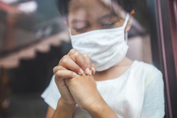 Obraz na płótnie Canvas Asian child girl wearing protection mask praying for a new day freedom to coronavirus Covid-19 and stay at home quarantine from the coronavirus Covid-19 and air pollution pm2.5.