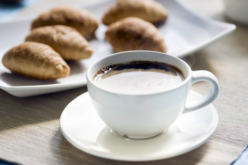 Breakfast, fresh croissants on a plate and a Cup of black coffee