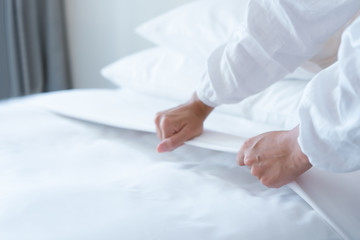 Female Hand set up white bed sheet in bedroom