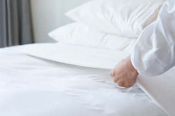 Obraz na płótnie Canvas Female Hand set up white bed sheet in bedroom