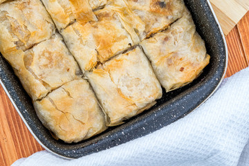 Apple pie homemade strudel in a baking iron plate on a wooden table just out of the oven. Pie with apples, raisins and cinnamon, sweet pastries