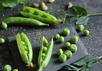 Gardening and agriculture. Green peas in pods on black board on a black background. Harvest green paes. Background image, copy space