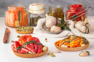 Fermented red hot peppers to enhance immunity with spices on a light wooden table against a background of glass jars with pickled products