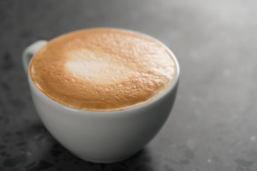 Fresh cappuccino in white cup on concrete background