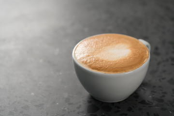 Fresh cappuccino in white cup on concrete background