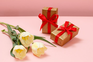 Gift boxes with tulip flowers on a pink background.