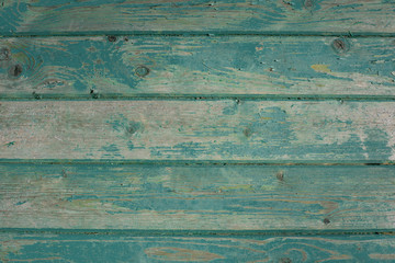 old wooden planks with peeling paint. The boards were painted blue and green. The paint was cracked and peeling.