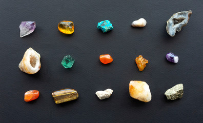Composition of gems, crystals and minerals of different geological rocks on a black background. A...