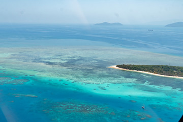 Island in Great Barrier Reef Blue Sea view. Beautiful aqua & turquoise waters, with sand, coral reef patterns in the ocean. View from helicopter, on vacation. Tropical, paradise, holiday concepts