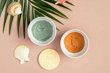Fototapeta na wymiar Clay masks in bowls for face treatment with tropical palm leaf, top view. SPA natural organic cosmetics, facial skincare concept
