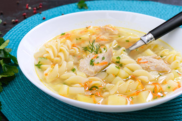 Dietary chicken soup with fusilli in a white bowl on a black background