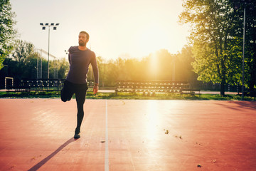 Male doing stretching exercise, preparing for a morning workout in the park