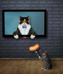 The multi colored cat is coming out from the TV screen at home. The black rat feeds him a sausage on a fork.