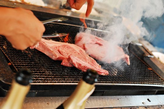 Close-up Of Cropped Hands Preparing Meat On Barbecue Grill