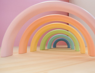 Abstract figures from elements of the children's designer wooden pastel rainbow on a wooden podium.