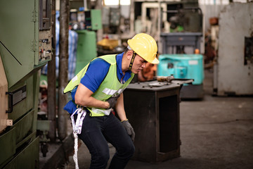 First Aid. Engineering supervisor talking on walkie talkie communication while his coworker lying unconscious at industrial factory. Professional engineering teamwork concept.