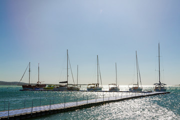 Fototapeta premium Several yachts in a row are parked at the pier. Blue sky and sea in the background. Skyline