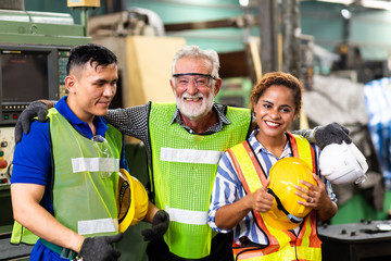 Man and Woman engineering wearing safety goggles and hard hats giving high five and celebrating success. Metal lathe industrial manufacturing factory