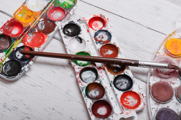 Professional watercolor aquarell paints in box with brushes on old white wooden board