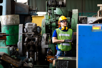 Portrait Engineer man working with computer laptop or tablet at factory Equipment. Chief Engineer in the Hard Hat Holds Laptop at the industrial facility.