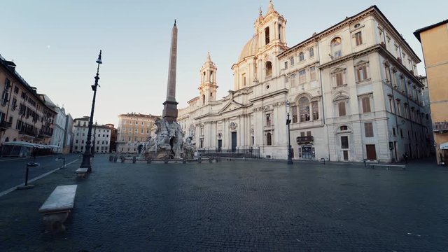Walking over empty Piazza Navona, towards the fountain of the four rivers and Sant'Agnese in Agone cathedral, during sunrise, in Rome, Italy - Coronavirus pandemic