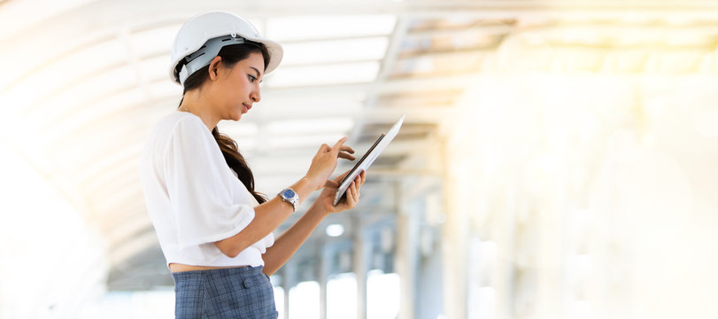 Portrait Of Beautiful Woman Serious Civil Engineer Working With Blueprint Documents On Construction Site. Engineering And Architecture Concept