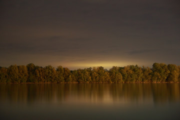 Fototapeta na wymiar Long exposure landscape photo about Danube river and forest at night; color image.
